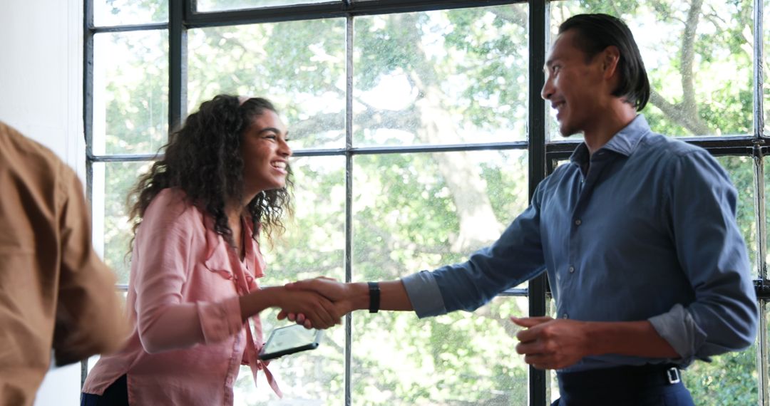 Colleagues Shaking Hands in Modern Office with Big Windows