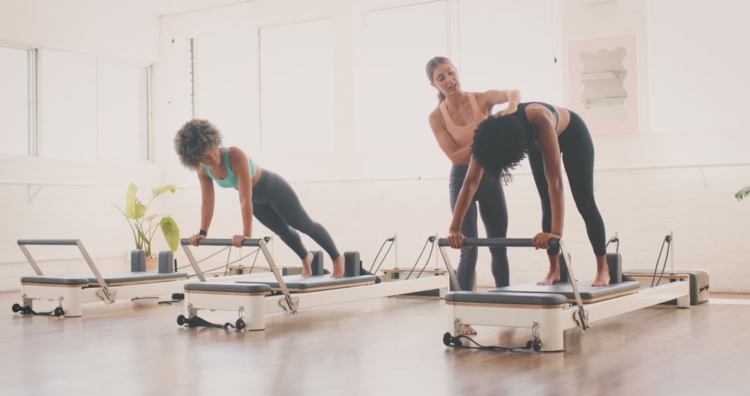 Women Engaged in Pilates Reformer Class in Bright Studio