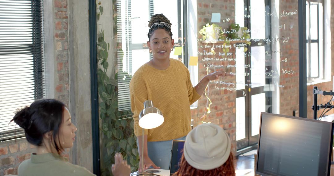 Woman presenting code on glass board in modern coworking office during team brainstorming