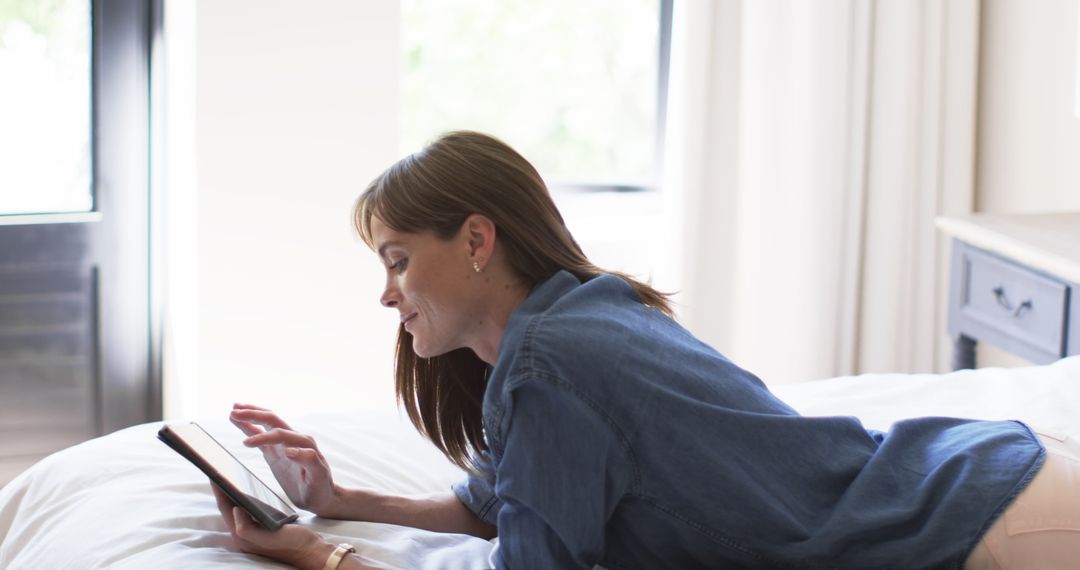 Middle-aged Woman Relaxing with Tablet Reading in Cozy Bedroom
