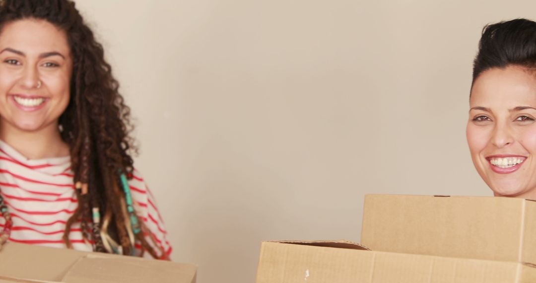 Two Happy Women Carrying Moving Boxes While Smiling - Free Images, Stock Photos and Pictures on Pikwizard.com