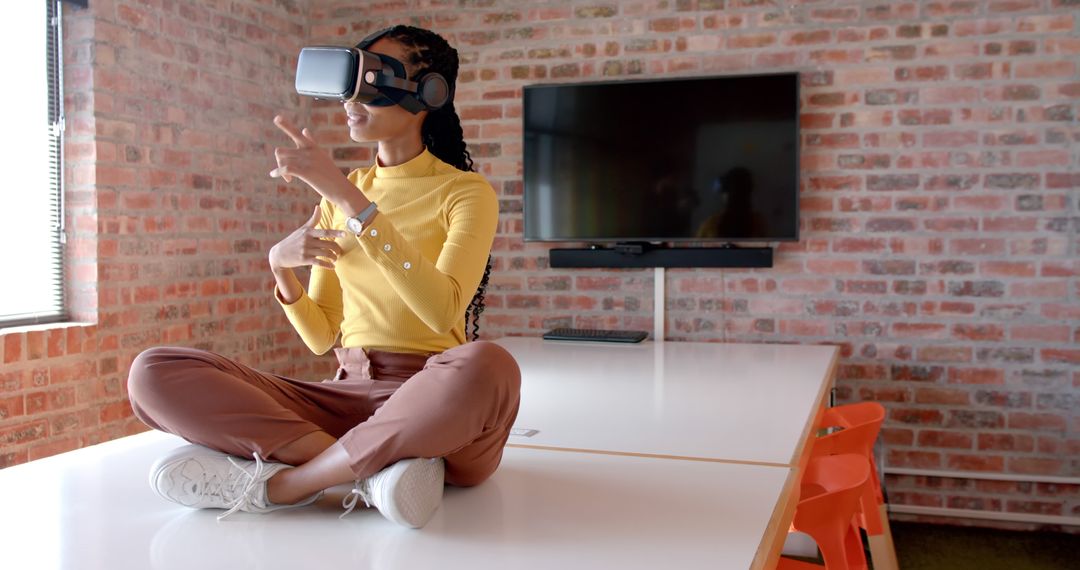 Woman Sitting on Desk Using Virtual Reality Headset in Modern Office - Free Images, Stock Photos and Pictures on Pikwizard.com