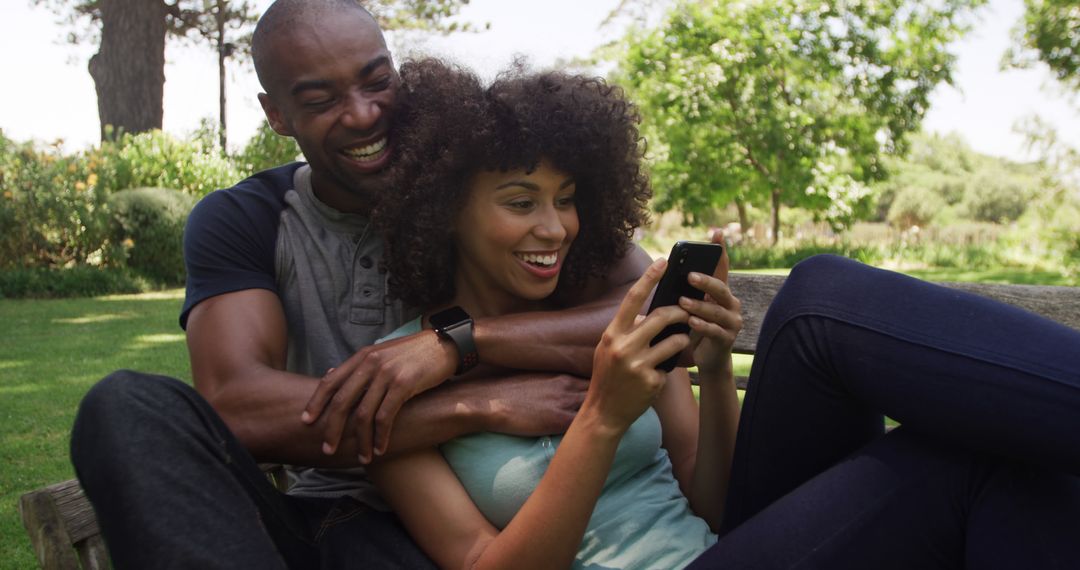 Joyful Couple Embracing While Browsing Smartphone Outdoors