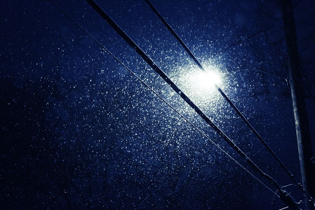 Serene snowfall illuminated by transformer streetlight at night
