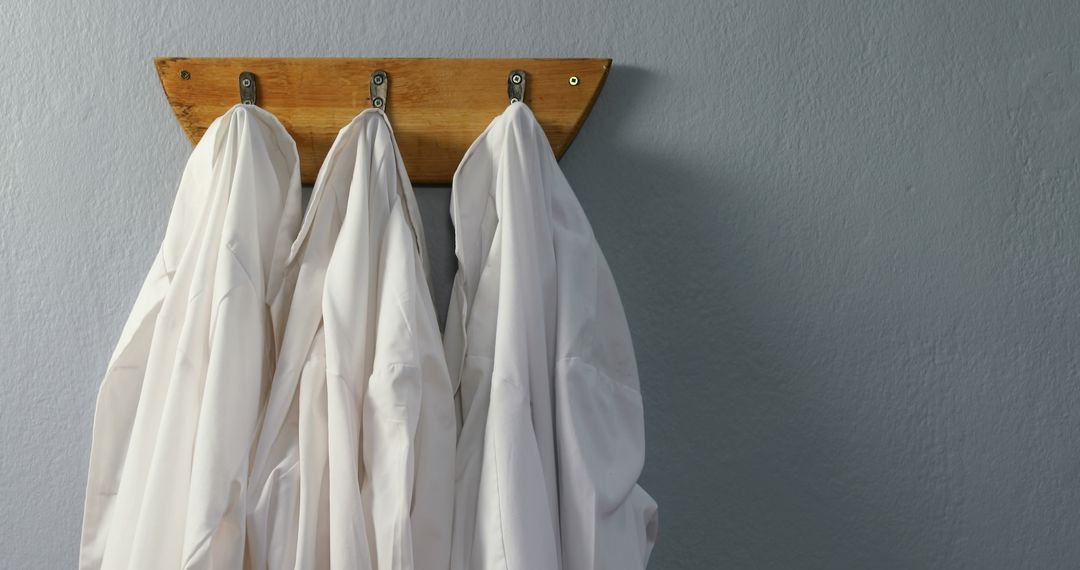 White Lab Coats Hanging on Wooden Rack in Professional Environment - Free Images, Stock Photos and Pictures on Pikwizard.com