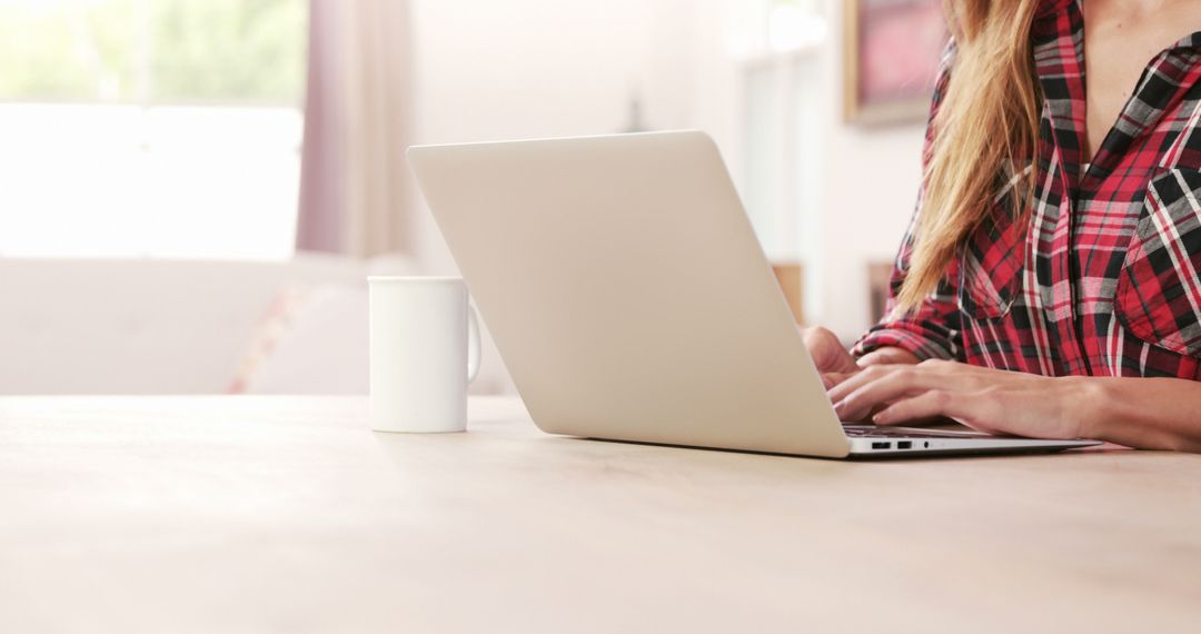 Woman Working on Laptop at Home with Coffee Mug on Wooden Table - Free Images, Stock Photos and Pictures on Pikwizard.com