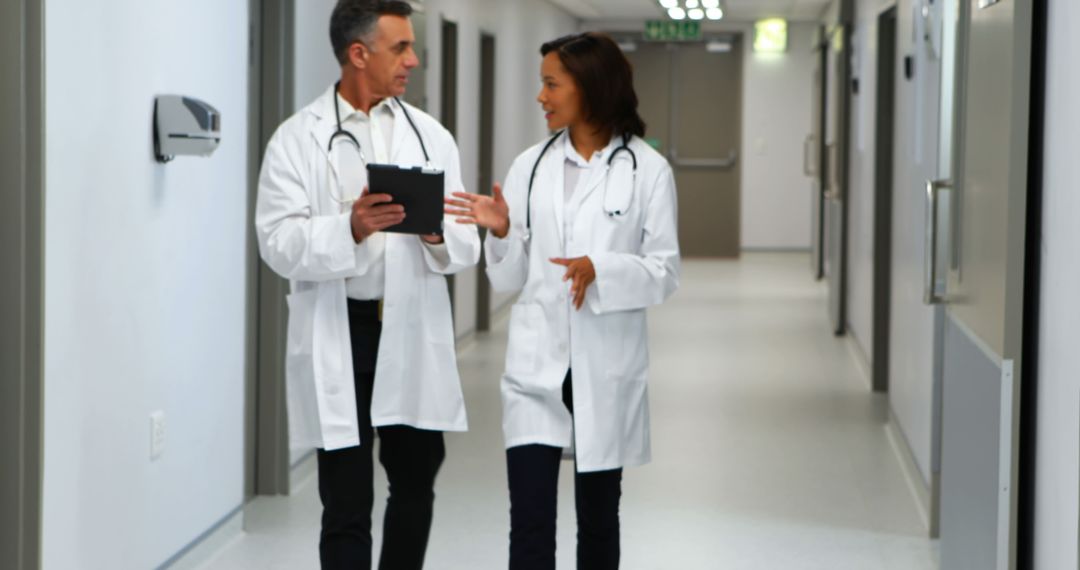 Doctors Discussing Patient Care Walking Through Hospital Corridor - Free Images, Stock Photos and Pictures on Pikwizard.com