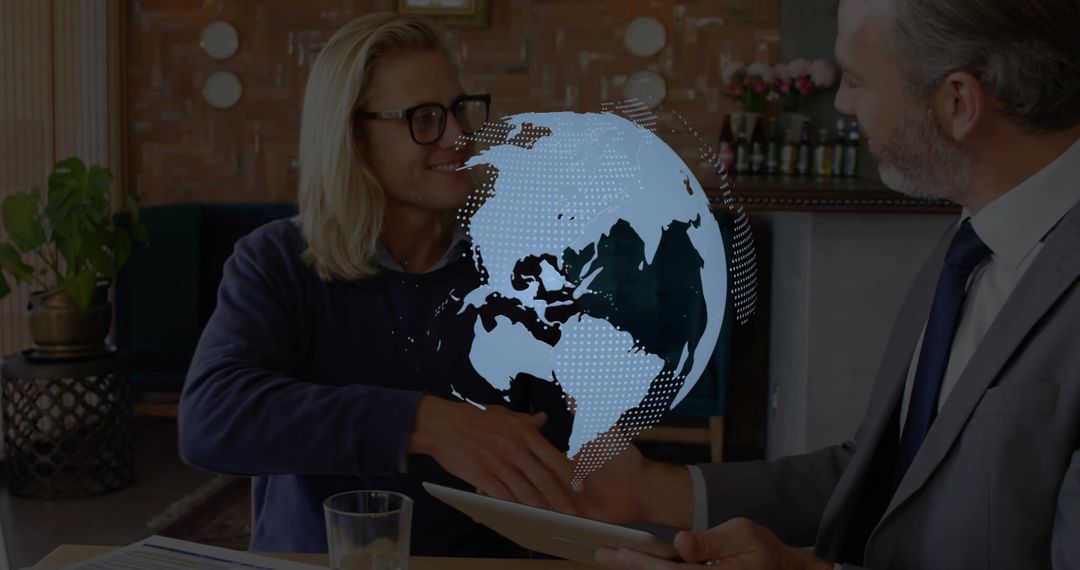 Business partners shaking hands over tablet with digital globe hologram in modern office