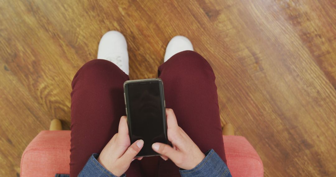 Person Holding Smartphone Sitting on Wooden Floor - Free Images, Stock Photos and Pictures on Pikwizard.com