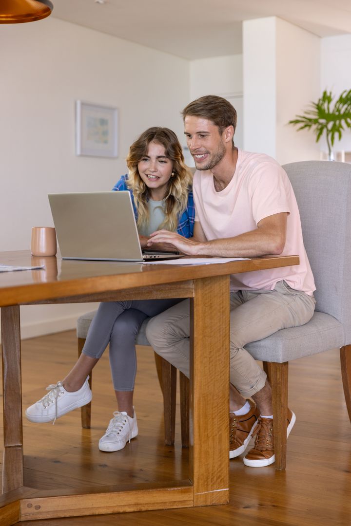 Couple Using Laptop Together at Home Dining Table