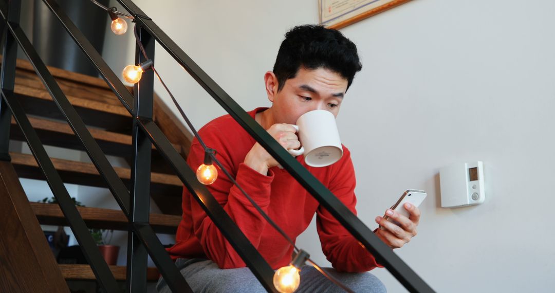 Man Drinking Coffee and Using Smartphone at Home on Stairs - Free Images, Stock Photos and Pictures on Pikwizard.com