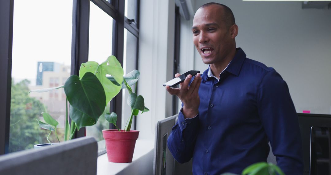 Businessman Speaking into Smartphone, Standing Near Window - Free Images, Stock Photos and Pictures on Pikwizard.com