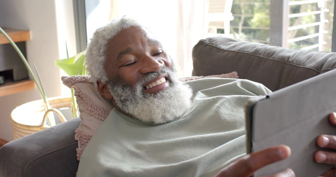 Senior Man Relaxing with Tablet at Home: Staying Connected with Digital Keypad