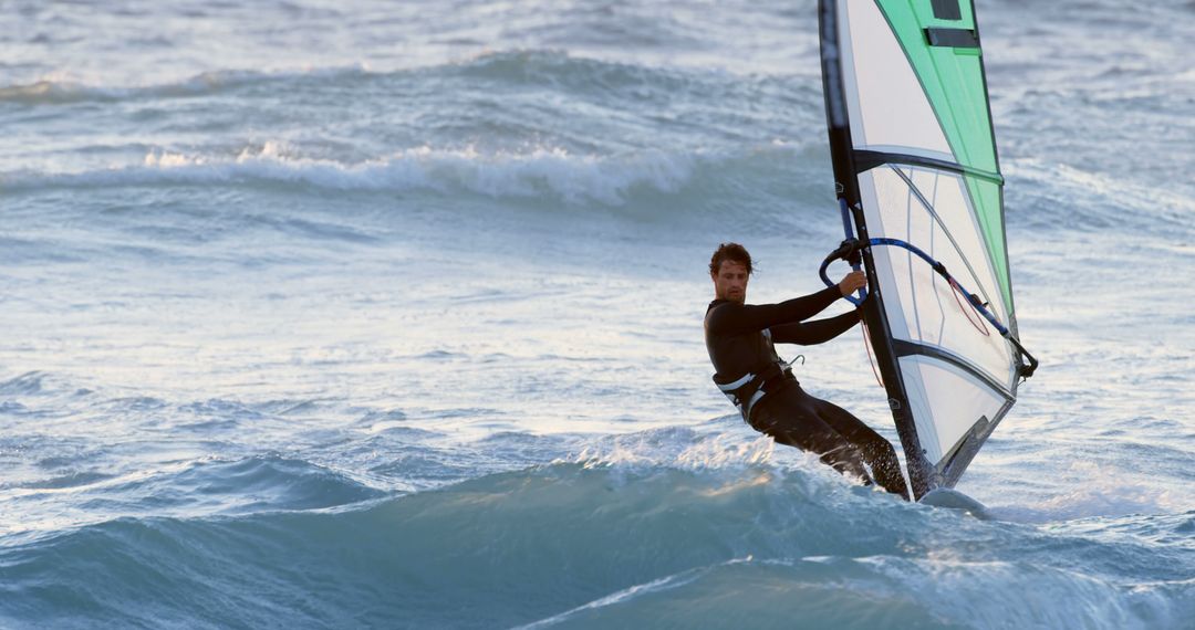 Young man windsurfing in rough ocean waters during sunset - Free Images, Stock Photos and Pictures on Pikwizard.com