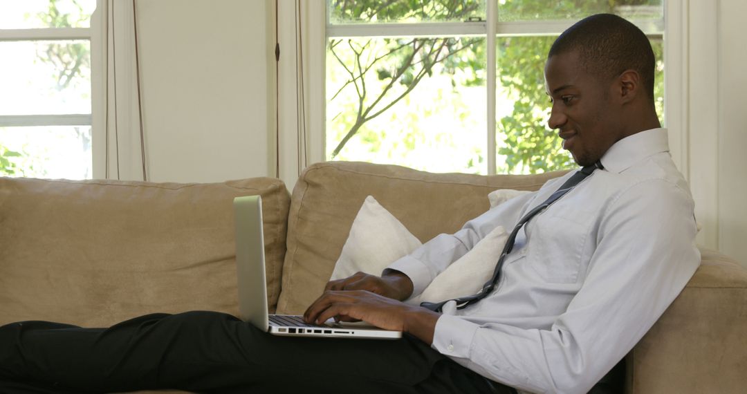 Professional Man Relaxing on Couch with Laptop Smiling Confidently