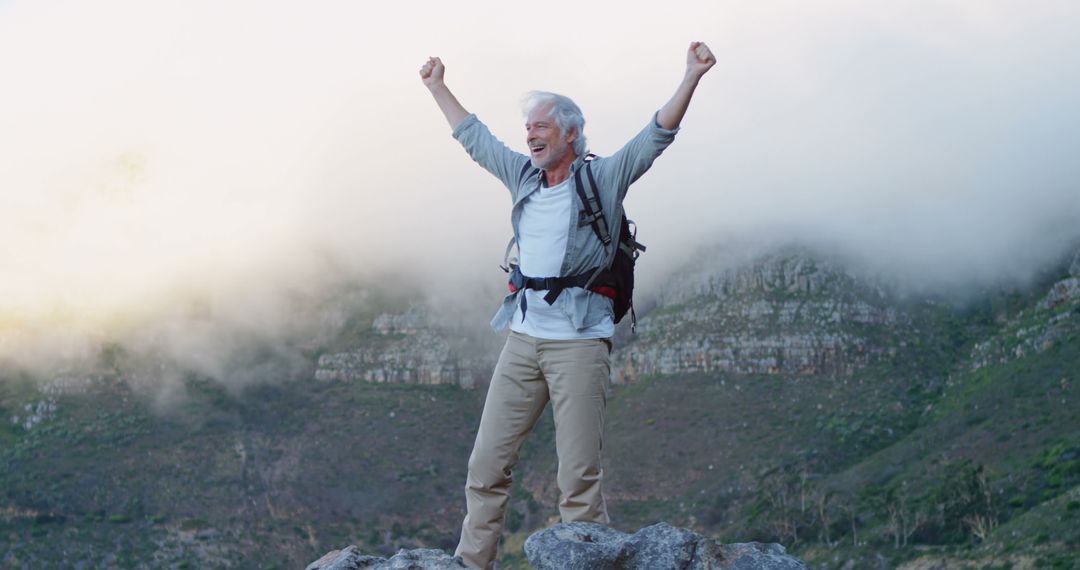 Caucasian man celebrates success on a mountain hike - Free Images, Stock Photos and Pictures on Pikwizard.com
