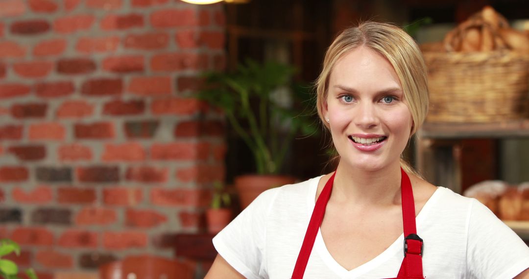 Smiling Female Bakery Worker in Red Apron - Free Images, Stock Photos and Pictures on Pikwizard.com