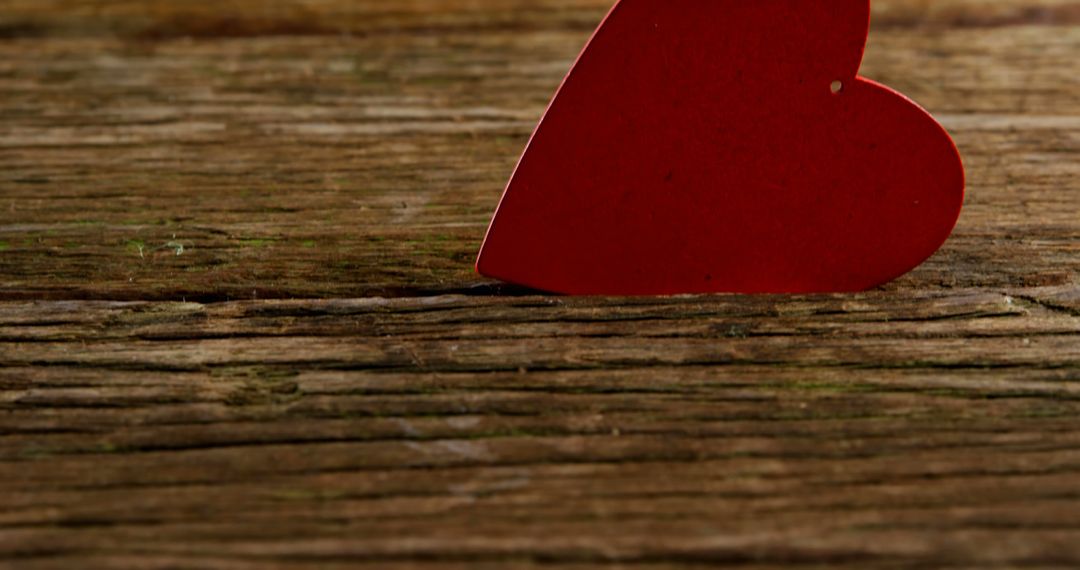 A red heart cutout rests on a rustic wooden surface, symbolizing love and romance, with copy space - Free Images, Stock Photos and Pictures on Pikwizard.com