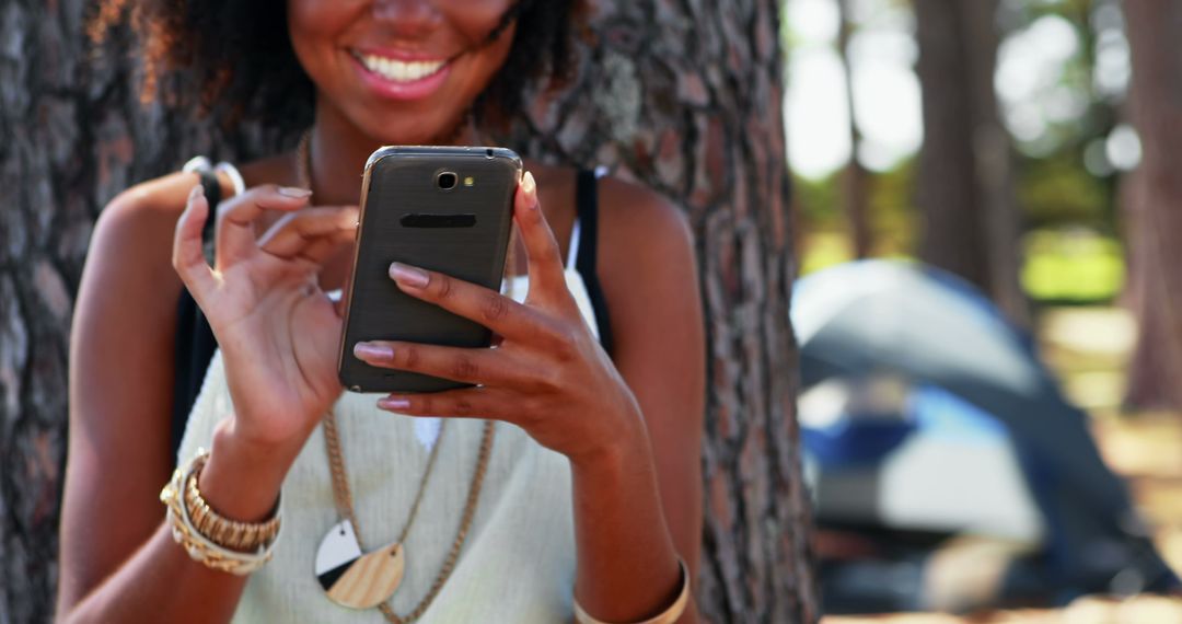 Woman Smiling While Using Smartphone in Outdoor Setting - Free Images, Stock Photos and Pictures on Pikwizard.com