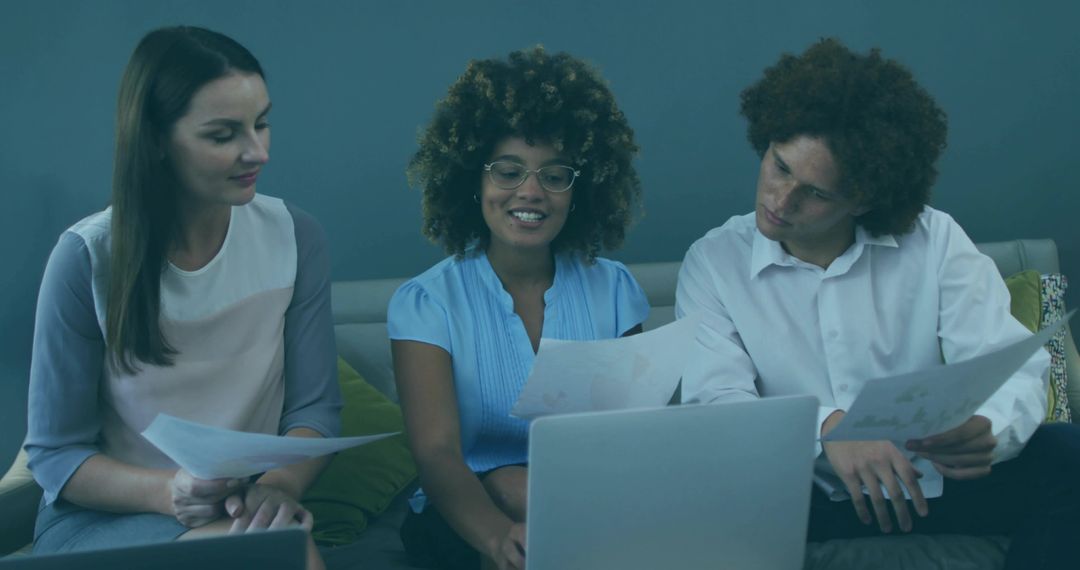 Diverse Team Collaborating with Laptops and Documents in Modern Office