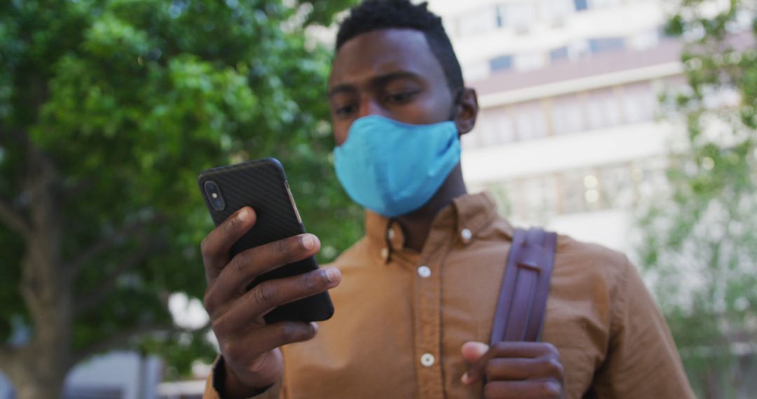 Man Wearing Face Mask Checking Smartphone in Urban Environment