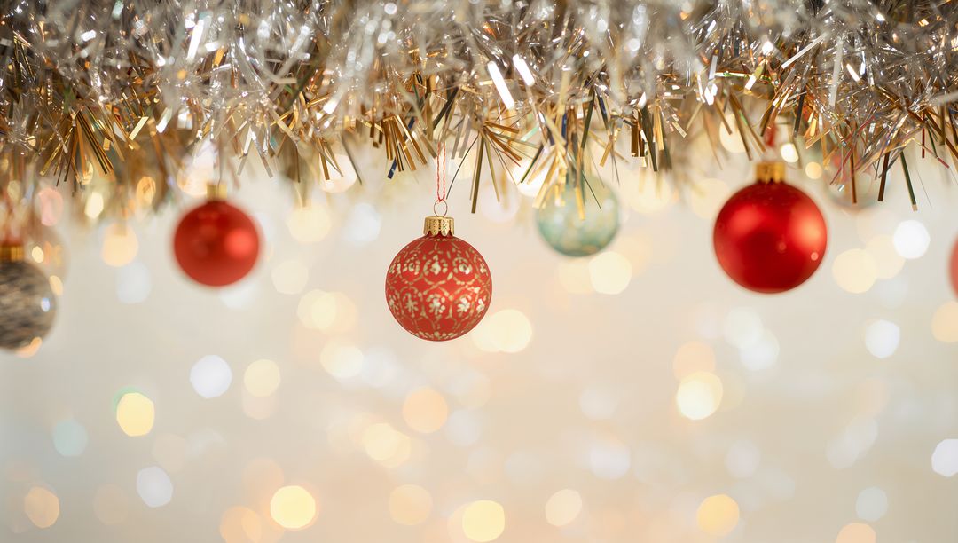Shimmering Red Patterned Bauble Hanging from Gold Tinsel with Warm Bokeh Lights