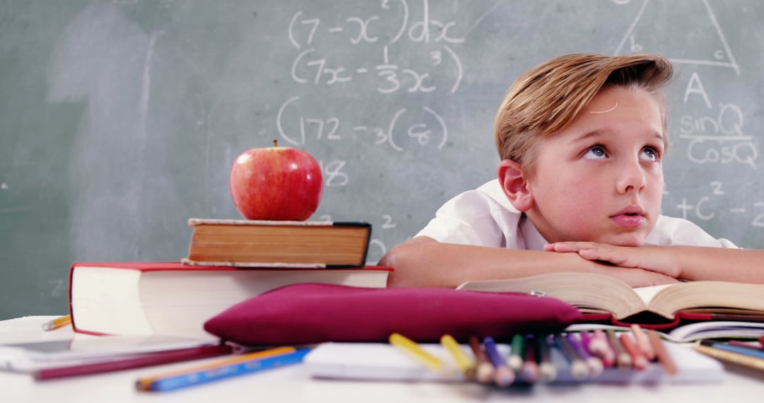 Pensive Child at School Desk Surrounded by Books and Chalkboard Equations - Free Images, Stock Photos and Pictures on Pikwizard.com