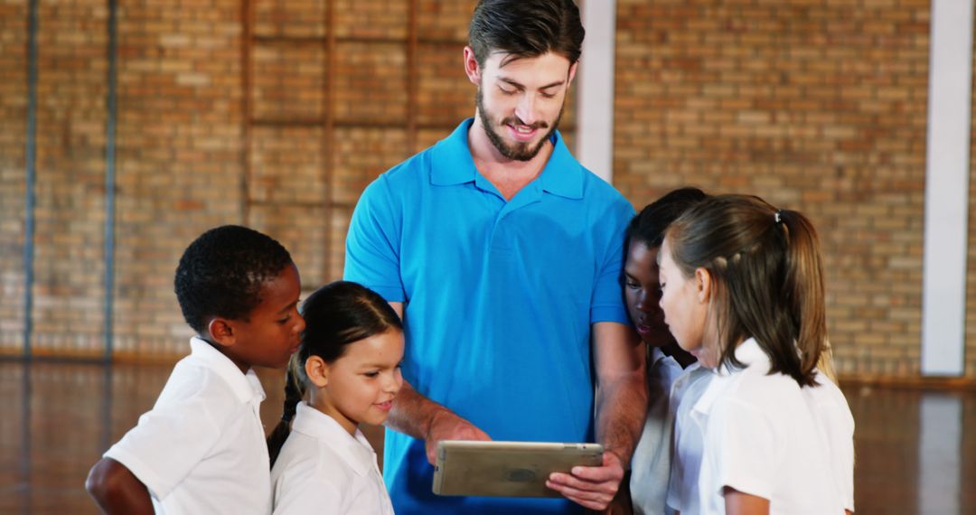 Teacher Showing Tablet to Elementary Students in Gymnasium - Free Images, Stock Photos and Pictures on Pikwizard.com