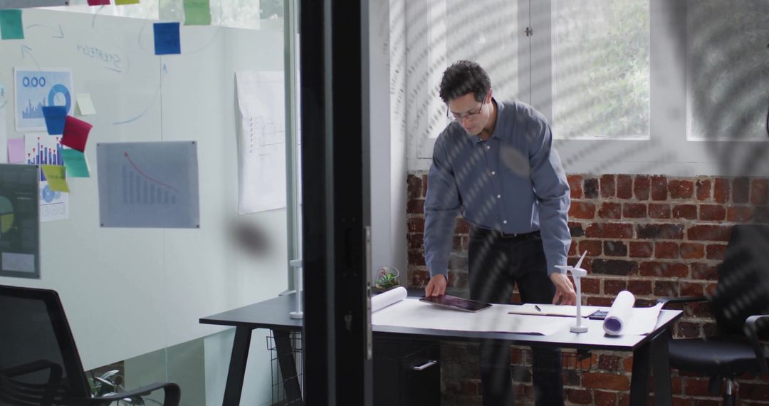 Businessman in Modern Office Analyzing Data with Tablet