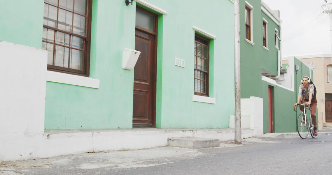 Woman Riding Bicycle Along Colorful Houses - Free Images, Stock Photos and Pictures on Pikwizard.com