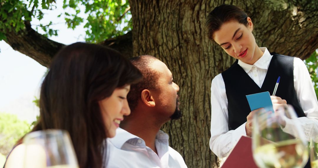 Waitress Taking Order from Couple at Sunny Outdoor Cafe