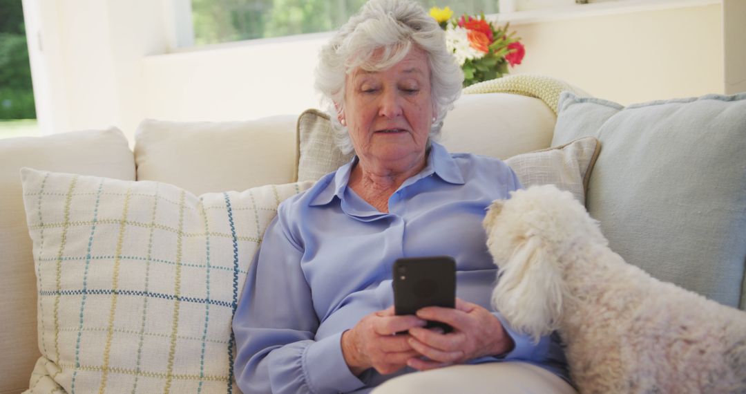 Elderly Woman Using Smartphone with Curious Dog on Sofa - Free Images, Stock Photos and Pictures on Pikwizard.com