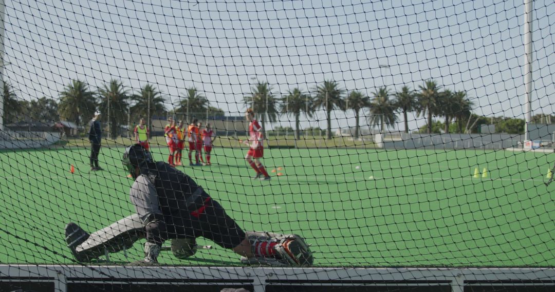 Field hockey goalkeeper training on green turf with players in background - Free Images, Stock Photos and Pictures on Pikwizard.com