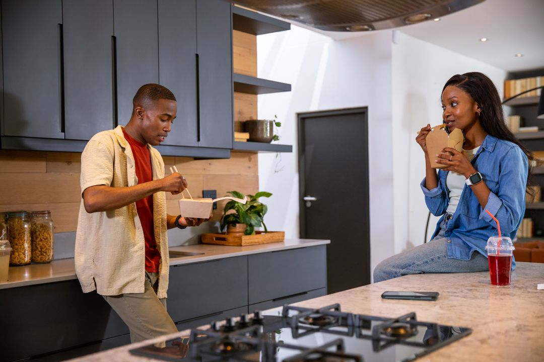Friends Enjoying Takeout Food with Chopsticks in Modern Kitchen
