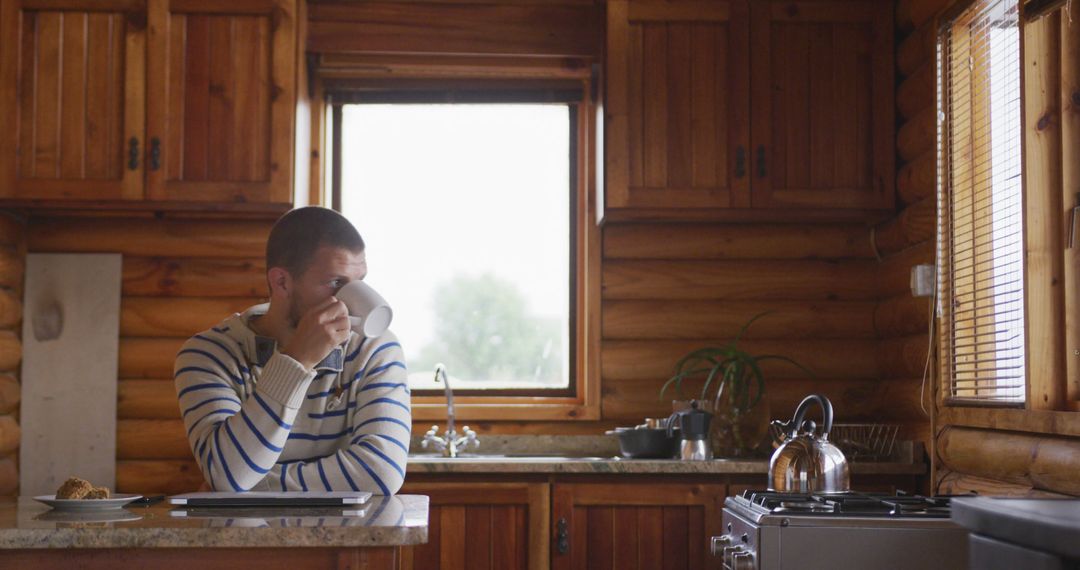 Man Drinking Coffee in Cozy Rustic Cabin Kitchen - Free Images, Stock Photos and Pictures on Pikwizard.com