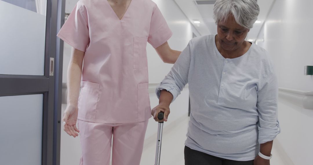 Nurse Assisting Elderly Woman with Walking Stick in Hospital Corridor - Free Images, Stock Photos and Pictures on Pikwizard.com