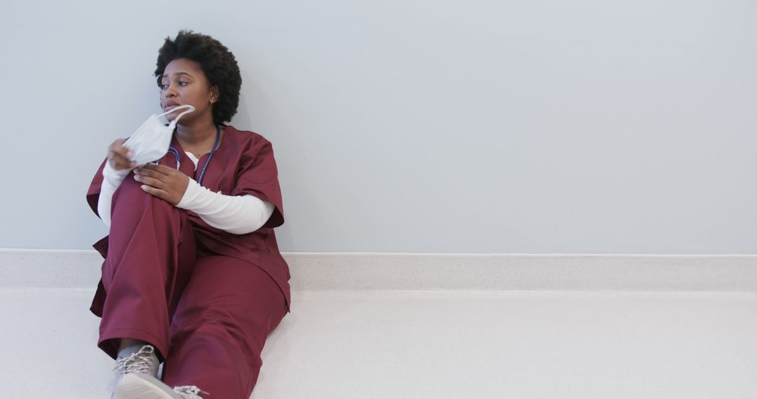 Tired Nurse Sitting on Hospital Floor Taking Break - Free Images, Stock Photos and Pictures on Pikwizard.com