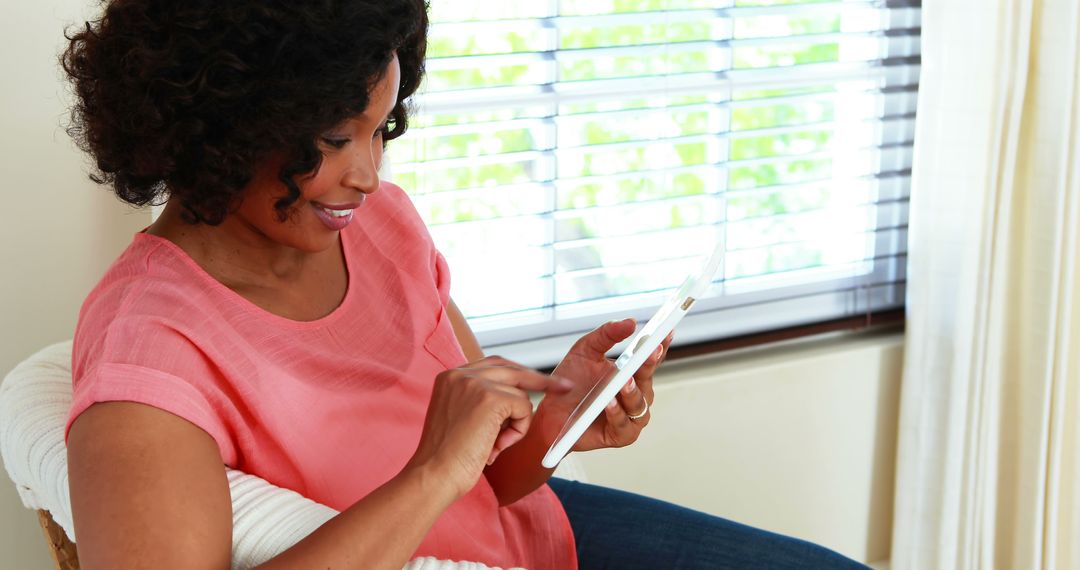 Smiling Woman Using Tablet Device at Home Near Window - Free Images, Stock Photos and Pictures on Pikwizard.com