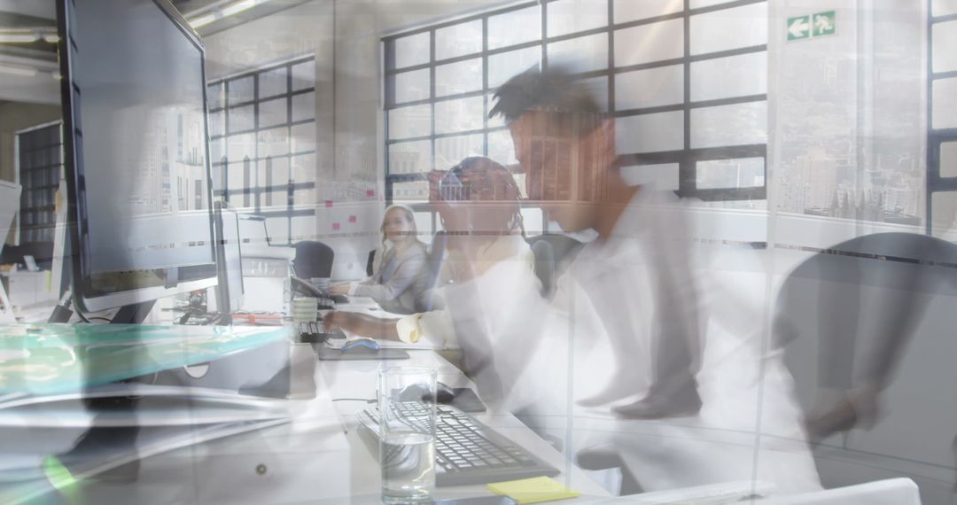 Overwhelmed businessman working at cluttered desk in modern office, blurred motion stress