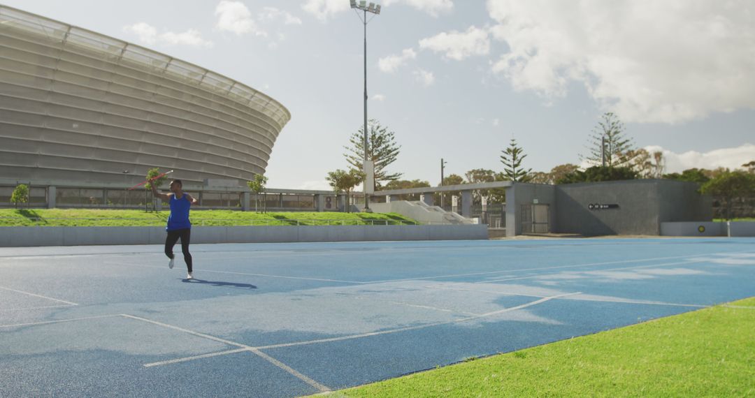 Athlete running on track near modern stadium on sunny day - Free Images, Stock Photos and Pictures on Pikwizard.com