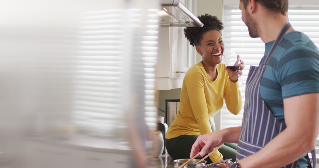 Image of happy diverse couple preparing meal, drinking wine and having fun in kitchen - Free Images, Stock Photos and Pictures on Pikwizard.com