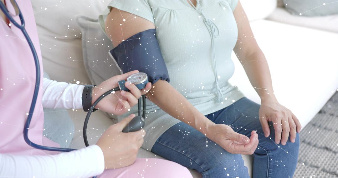 Nurse measuring blood pressure on woman sitting on sofa during home health care visit
