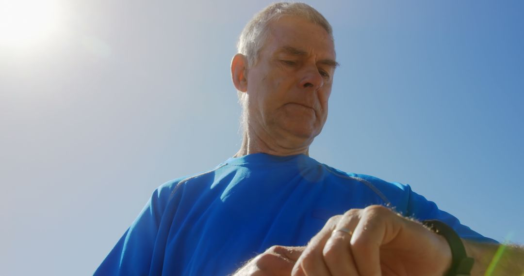 Senior Man on Promenade Checks Smartwatch in Sunlight