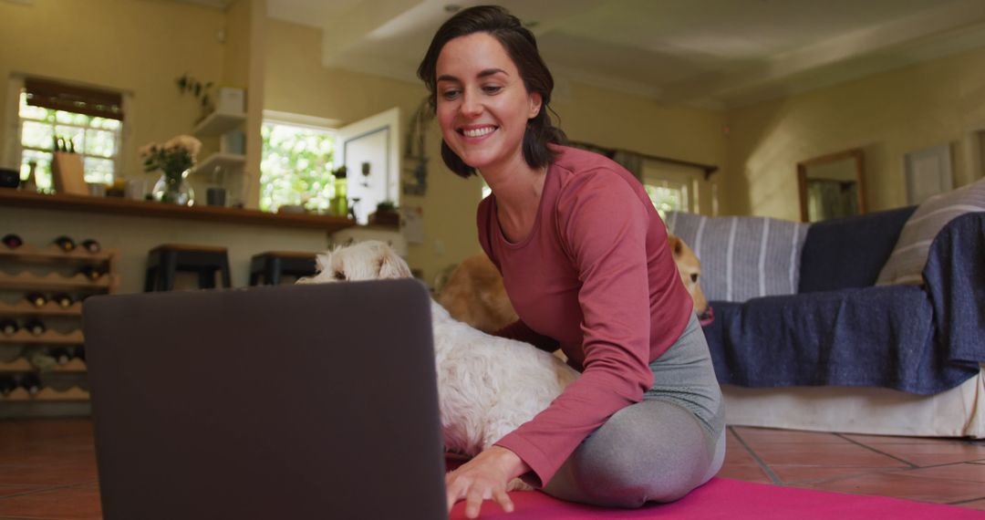 Caucasian woman exercising with her pet dog using laptop at home - Free Images, Stock Photos and Pictures on Pikwizard.com