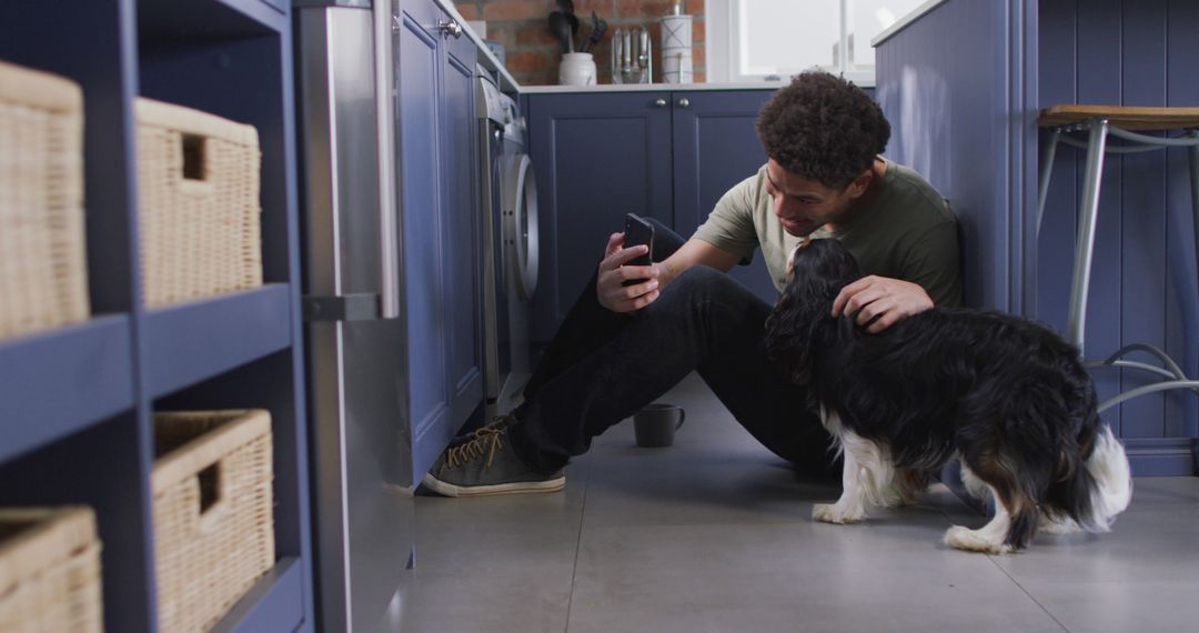 Man Sitting in Kitchen Enjoying Video Call with Smartphone and Pet Dog - Free Images, Stock Photos and Pictures on Pikwizard.com