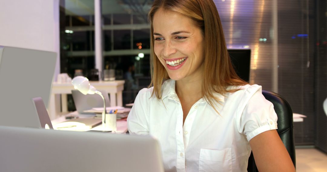 Smiling Woman Working Late in Office on Laptop - Free Images, Stock Photos and Pictures on Pikwizard.com