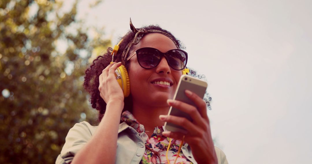 Young Woman Enjoying Music on Smartphone in Outdoors Setting - Free Images, Stock Photos and Pictures on Pikwizard.com