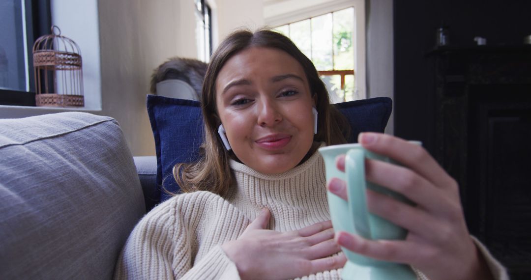 Young Woman Relaxing on Couch with Coffee and Earbuds - Free Images, Stock Photos and Pictures on Pikwizard.com