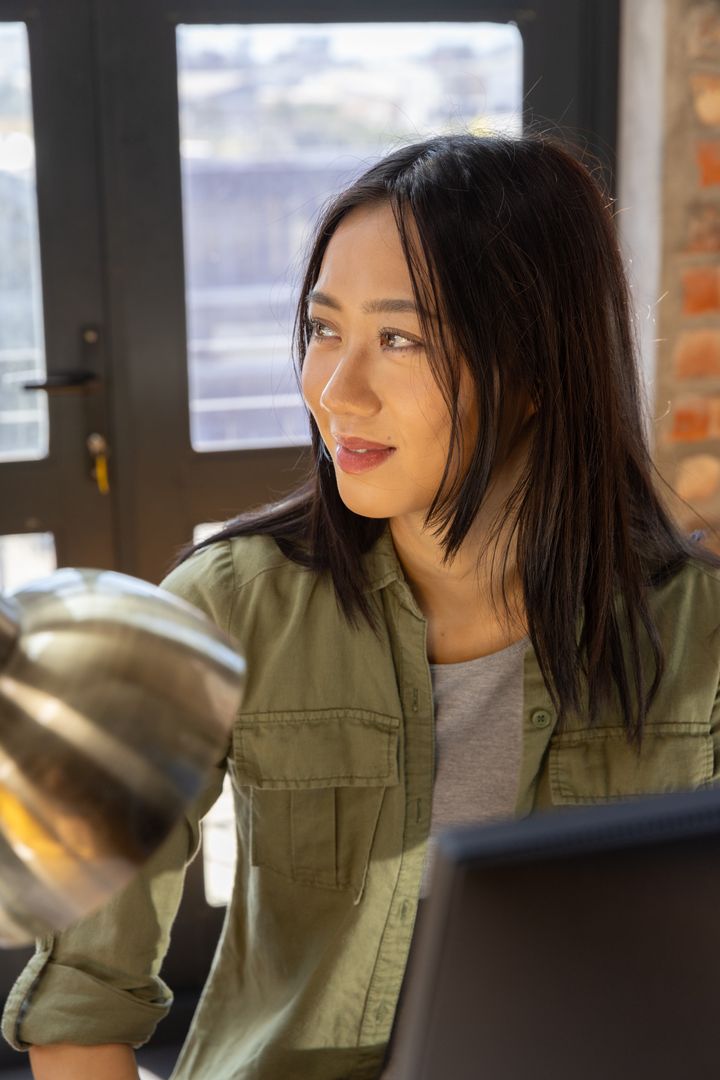 Thoughtful Woman in Modern Office Space with Laptop