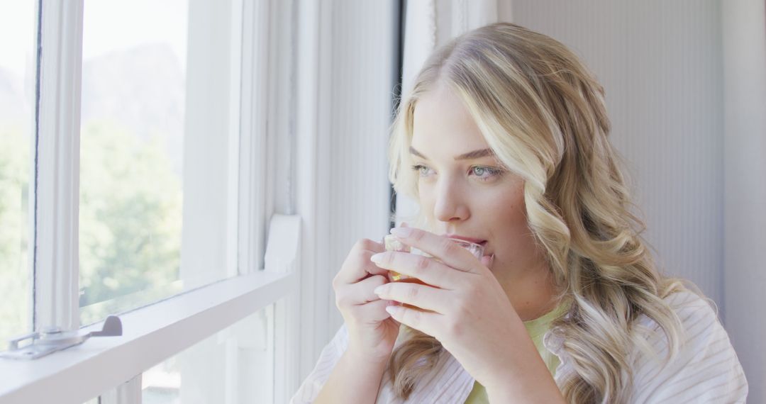 Relaxed Woman with Blonde Hair Drinking Tea by Window - Free Images, Stock Photos and Pictures on Pikwizard.com